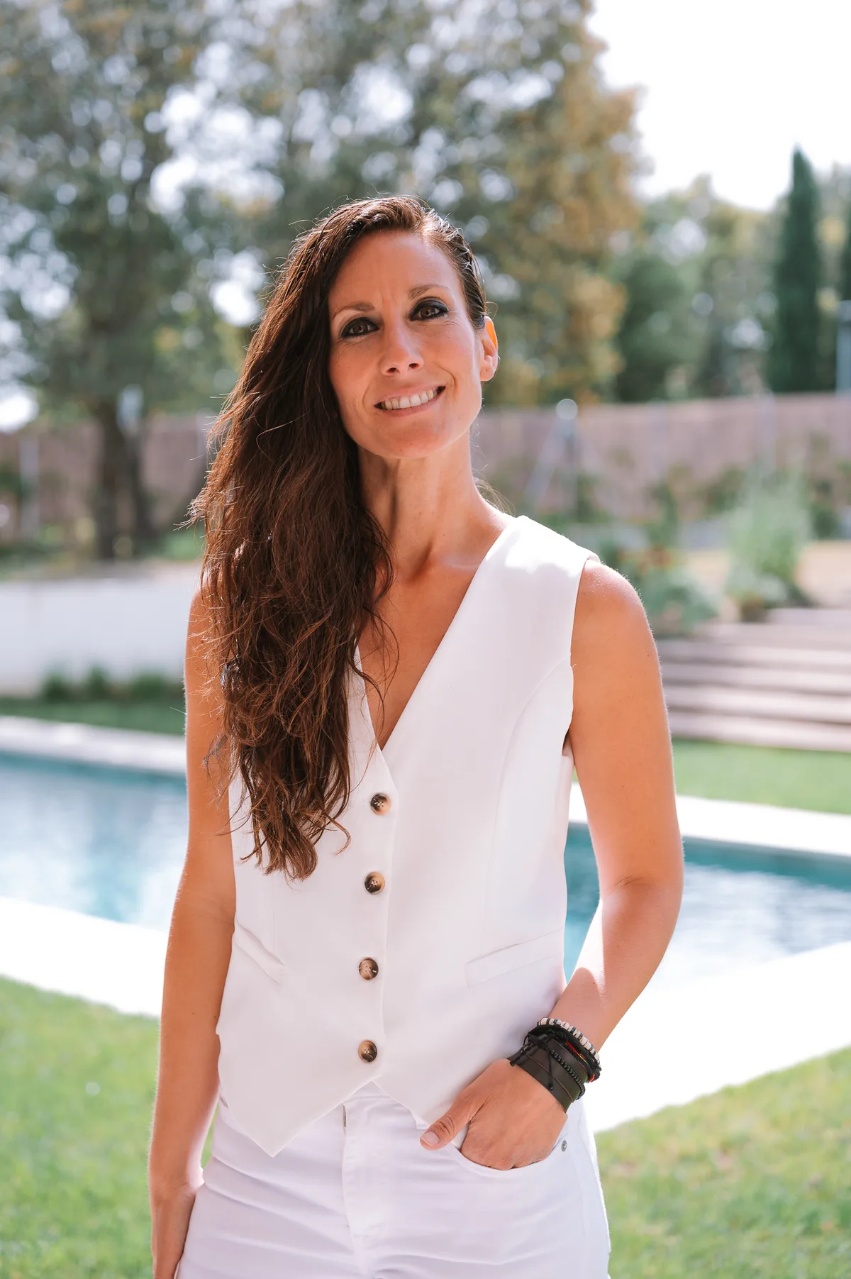 Ana Pedroche de pie al aire libre, serena, con el jardín y la piscina al fondo